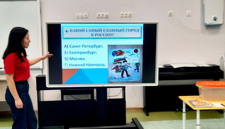 Фото 2. Ведущий викторины "Что мы знаем о своей стране и выборах" в рамках Дня молодого избирателя в МАДОУ №8 "Огонёк" объявляет вопрос, который показан на экране, и возможные к нему ответы для участников викторины.